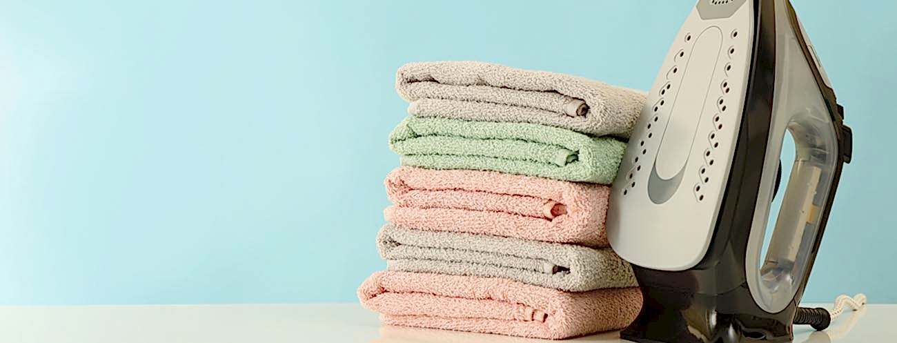 Modern iron and pile of towels on white table